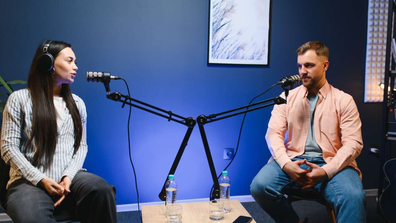 Kobieta i mężczyzna nagrywają podcast w studiu przy mikrofonach